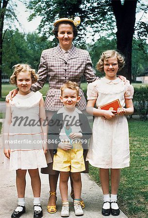 1950s MOTHER AND THREE CHILDREN ALL DRESSED UP POSING FOR PHOTO OUTDOORS