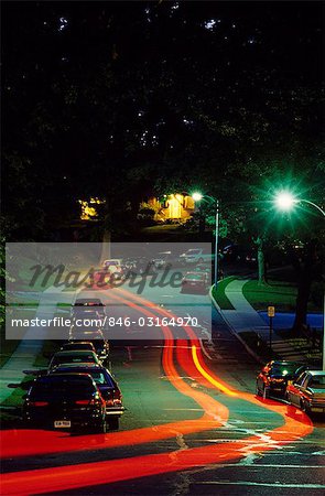 TRAÎNÉES DE LUMIÈRE DES PHARES DE VOITURE DANS UNE RUE RÉSIDENTIELLE DANS LA NUIT