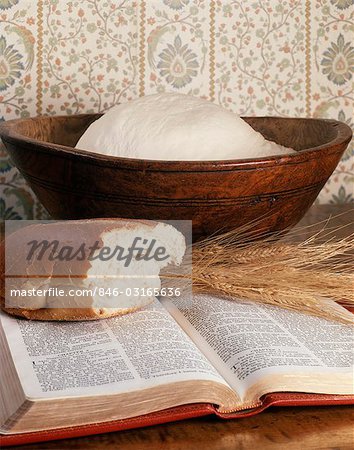 STILL LIFE OF BREAD DOUGH IN BOWL A LOAF OF BREAD AND WHEAT STALKS ON AN OPEN BIBLE