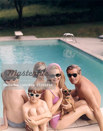 1960s 1970s FAMILY ALL WEARING SUNGLASSES BESIDE SWIMMING POOL