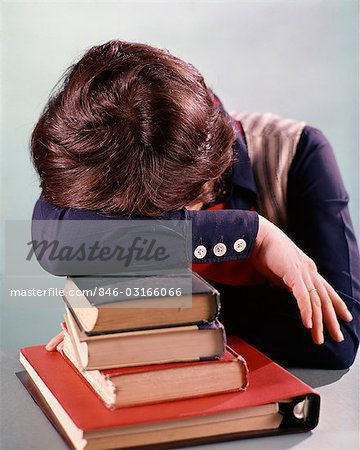 1960s 1970s FEMALE STUDENT HEAD DOWN ON PILE OF BOOKS ASLEEP EXHAUSTED