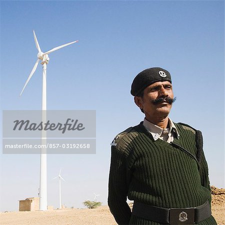 Soldat mit einer Windkraftanlage im Hintergrund, Jaisalmer, Rajasthan, Indien