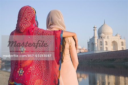 Rear view of two women with mausoleum in the background, Taj Mahal, Agra, Uttar Pradesh, India