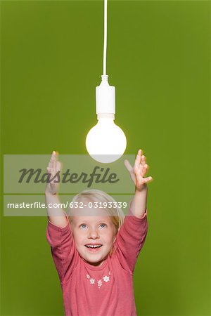 Little girl reaching for hanging light bulb