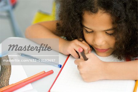 Little girl resting head on desk, drawing on graph paper