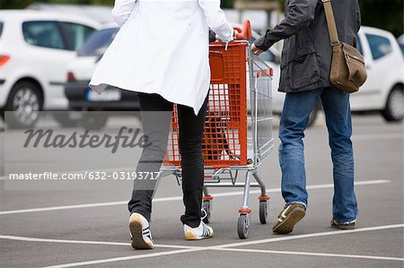 Shoppers pushing shopping cart in parking lot