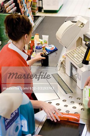 Cashier scanning purchases at checkout counter