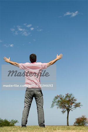 Homme debout en plein air avec bras soulevé, pleine longueur, vue arrière