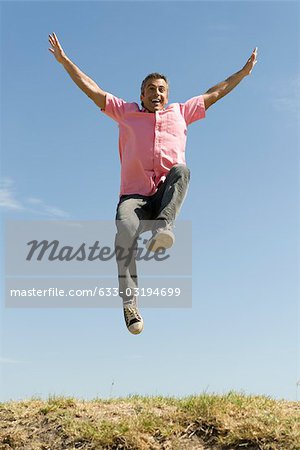Excited man jumping into the air with arms raised