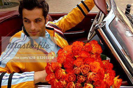 Junger Mann mit schwarzen Haaren sitzen in einem Auto mit einem Strauß Rosen, Nahaufnahme