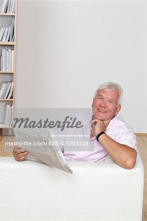 Senior man reading newspaper on couch