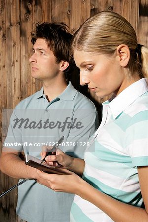 Two golf players with diary in front of wooden wall