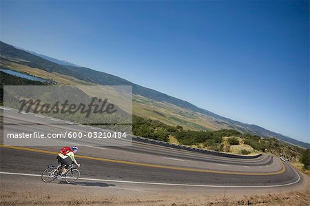 Woman Riding Her Bicycle Down a Hill Toward Steamboat Springs, Routt County, Colorado, USA