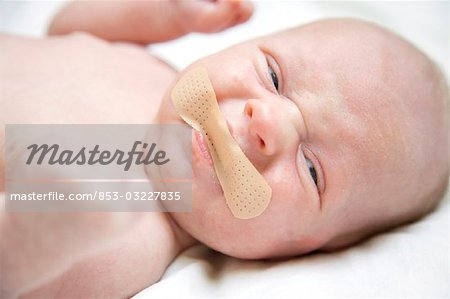 Baby boy with plaster on his mouth, close-up