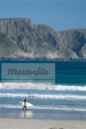 Achill Island, Co Mayo, Ireland; Surfer walking along Trawmore beach
