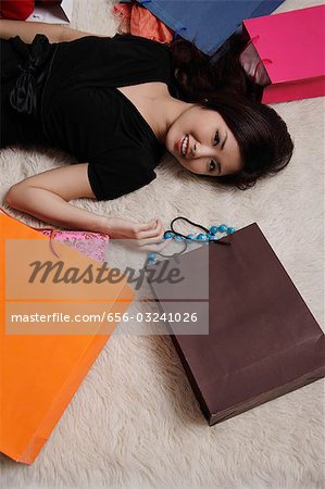 Femme chinoise pose sur plancher avec sacs à provisions