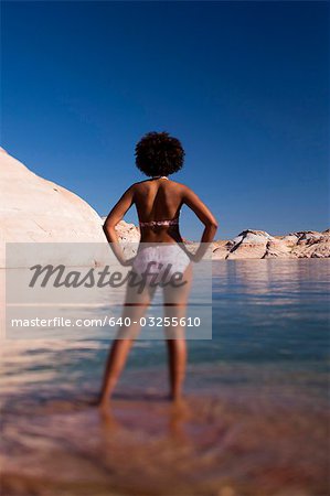 Woman standing in shallow water on rocky beach