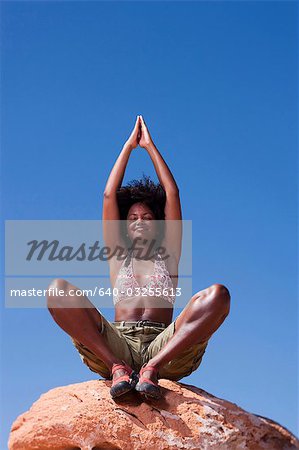 Woman sitting on rock looking up at sky