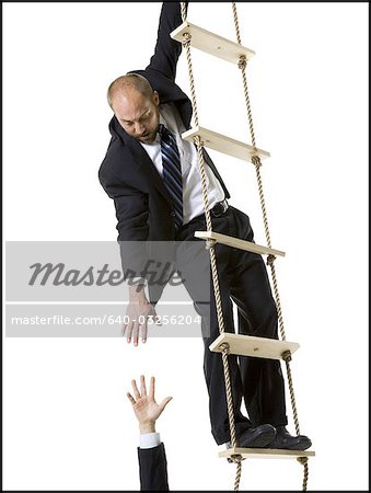 Businessman helping someone up ladder