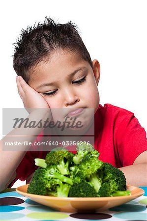 Boy with plate of broccoli frowning