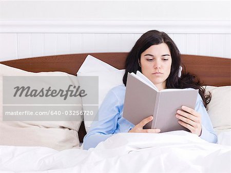Orem, Utah, USA, young woman reading book in bed