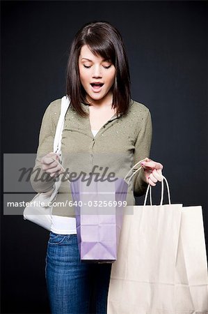 Studio portrait de jeune femme tenant des sacs à provisions