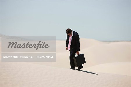 USA, Utah, Little Sahara, mid adult businessman walking on desert