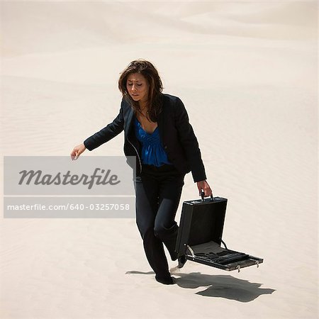 USA, Utah, Little Sahara, young businesswoman walking on desert carrying briefcase