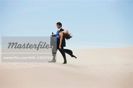 USA, Utah, Little Sahara, mid adult businessman carrying young woman on desert