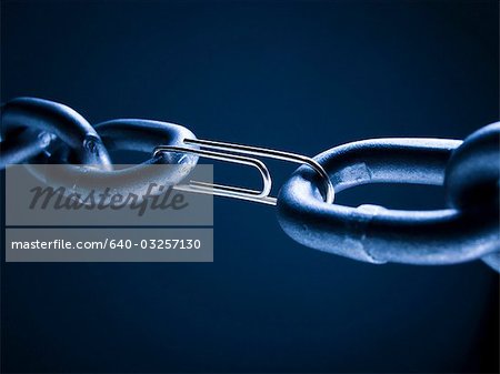 Chain linked with paper clip against blue background