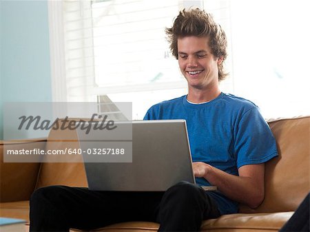 USA, Utah, Provo, jeune homme assis sur le canapé et utilisant un ordinateur portable