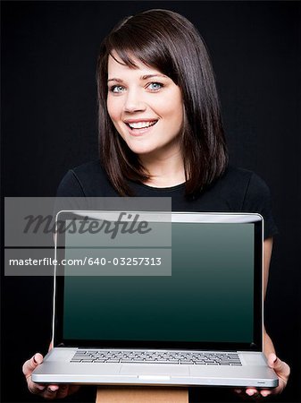 Young woman showing laptop, studio shot