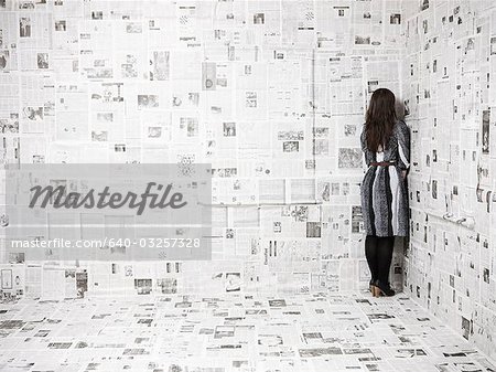 Rückansicht des jungen Frau stehen in der Ecke des Zimmers Zeitung abgedeckt, Studioaufnahme