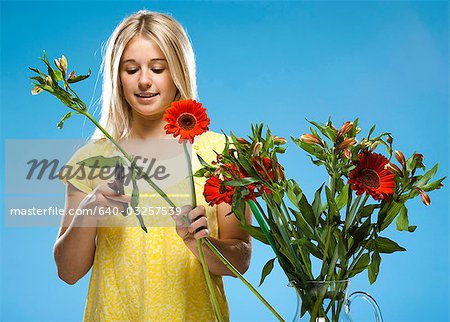 Young woman pruning flowers, studio shot