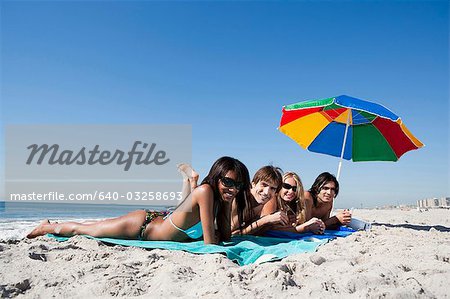 Four adults lying on the beach