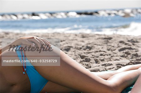 Hip of woman sunbathing on beach