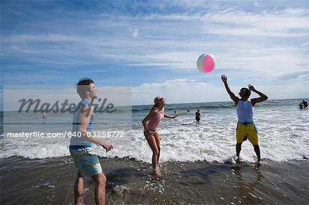 Three adults playing with a beach ball