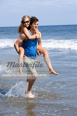 Homme portant la femme à la plage