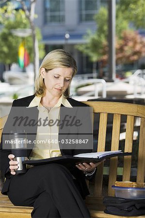 Femme d'affaires de lecture sur le banc de parc