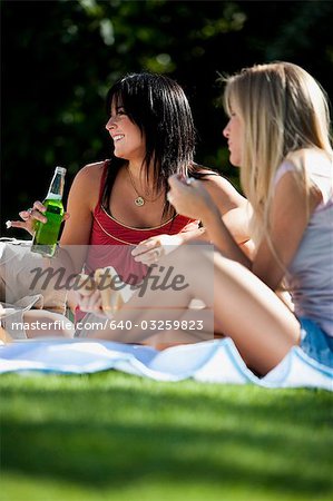 Freundinnen bei einem Picknick mit einer Öffnung ein Getränk