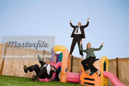 Three businesspeople playing on a jungle gym