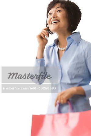 Femme tenant des sacs à provisions et parler au téléphone cellulaire