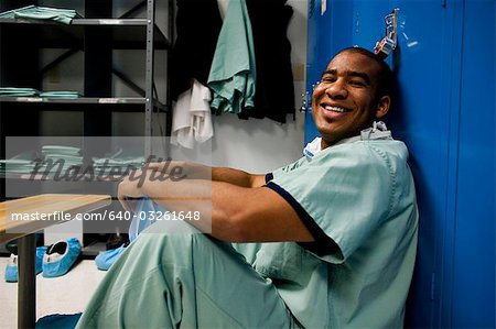 Male doctor in scrubs sitting in locker room