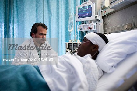 Doctor talking to boy in hospital bed