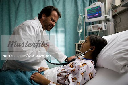 Doctor examining girl in hospital bed