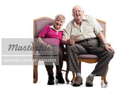 Elderly couple sitting in armchairs embracing