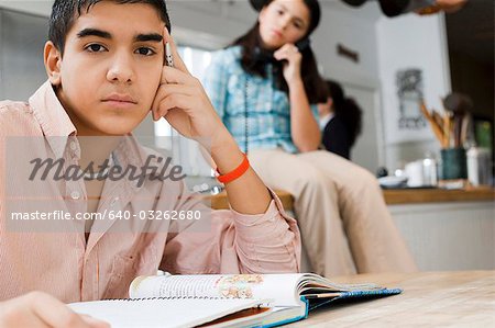 Boy doing homework with girl talking on phone