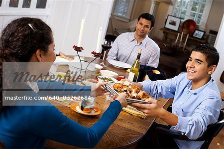 Boy passing chicken to man at table