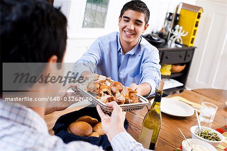 Boy passing chicken to man at table