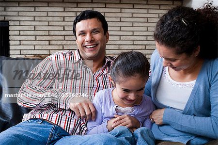 Man and woman tickling girl on sofa